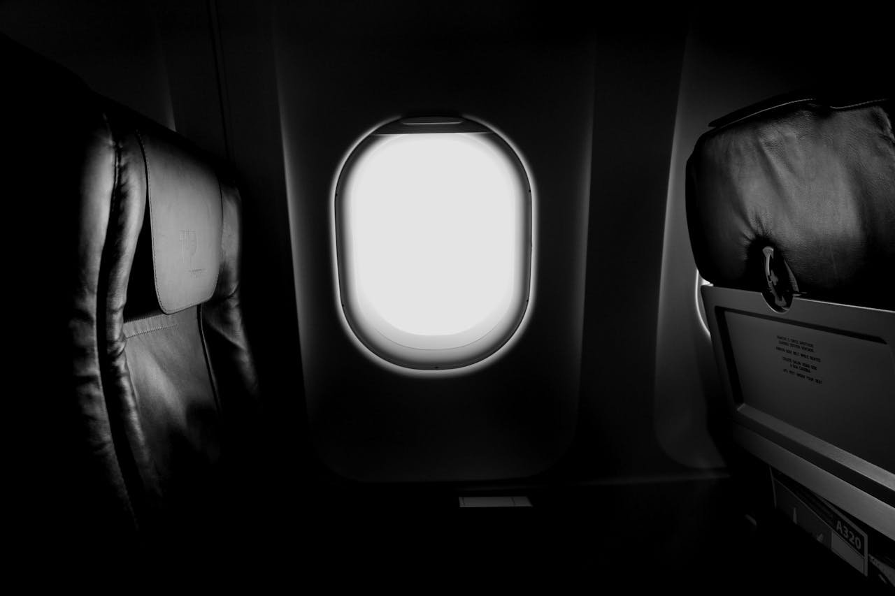 Black and white photo of an airplane's luxurious interior showcasing a leather seat and window view.